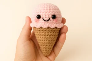 Close-up of the amigurumi ice cream cone crochet pattern, with a pink scoop and brown cone.
