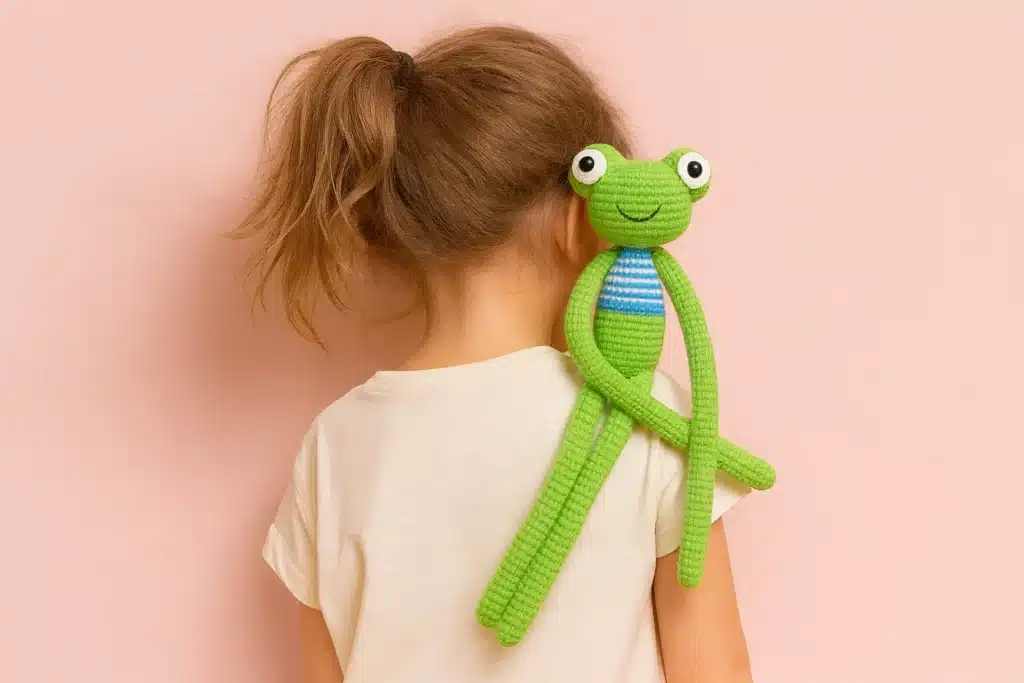 amigurumi leggy frog crochet toy on child shoulder