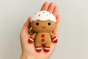 Gingerbread Cutie amigurumi from a free crochet gingerbread man pattern held in a hand