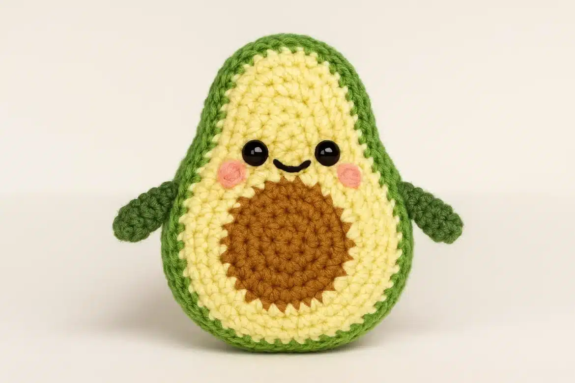Cute avocado amigurumi with green peel, blush cheeks, and tiny crochet hands.