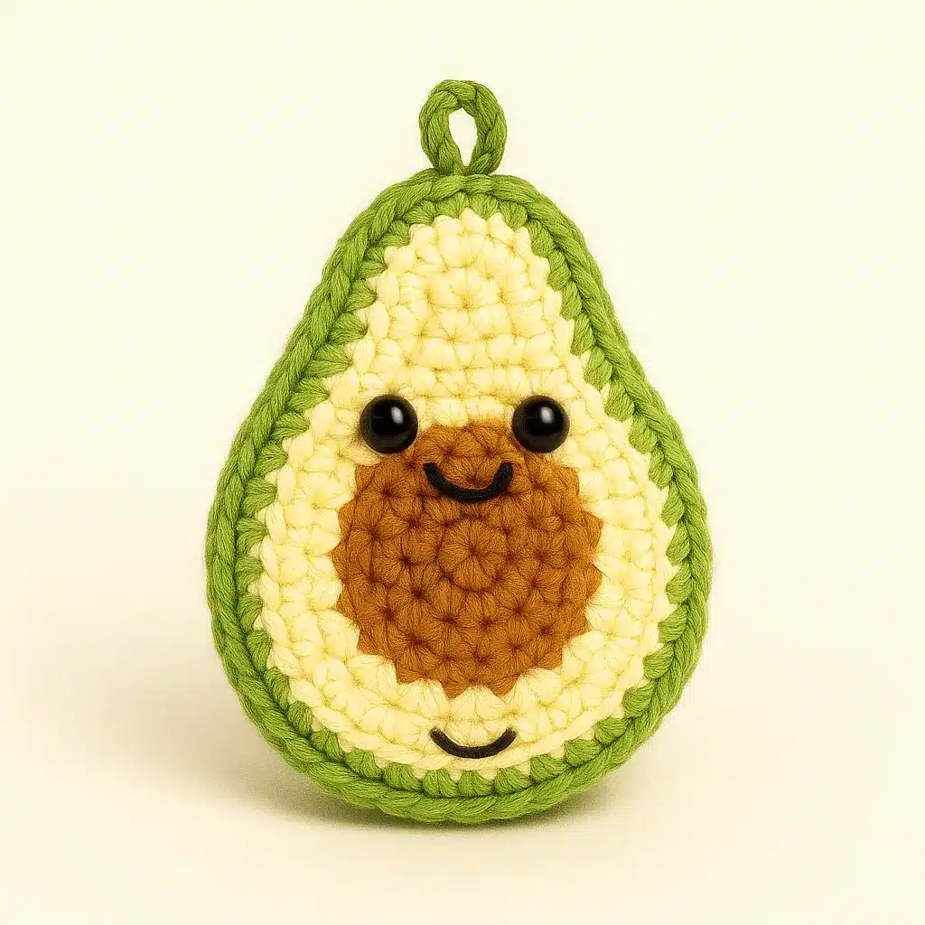 Avocado crochet keychain pattern sample with pit, loop and kawaii face.