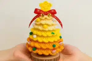 Rainbow ruffle crochet Christmas tree in yellow and orange held in hands