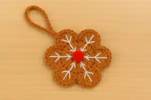 crochet gingerbread snowflake applique pattern ornament with hanging loop and red pompom