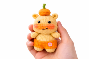 Hand holding Lulu the Capy-Hippo amigurumi with pumpkin hat — capybara crochet pattern free.
