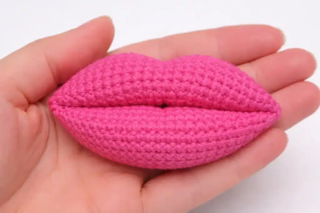 Finished puffy 3D crochet lips prop in bright pink held in the palm – crochet lips pattern for valentine.