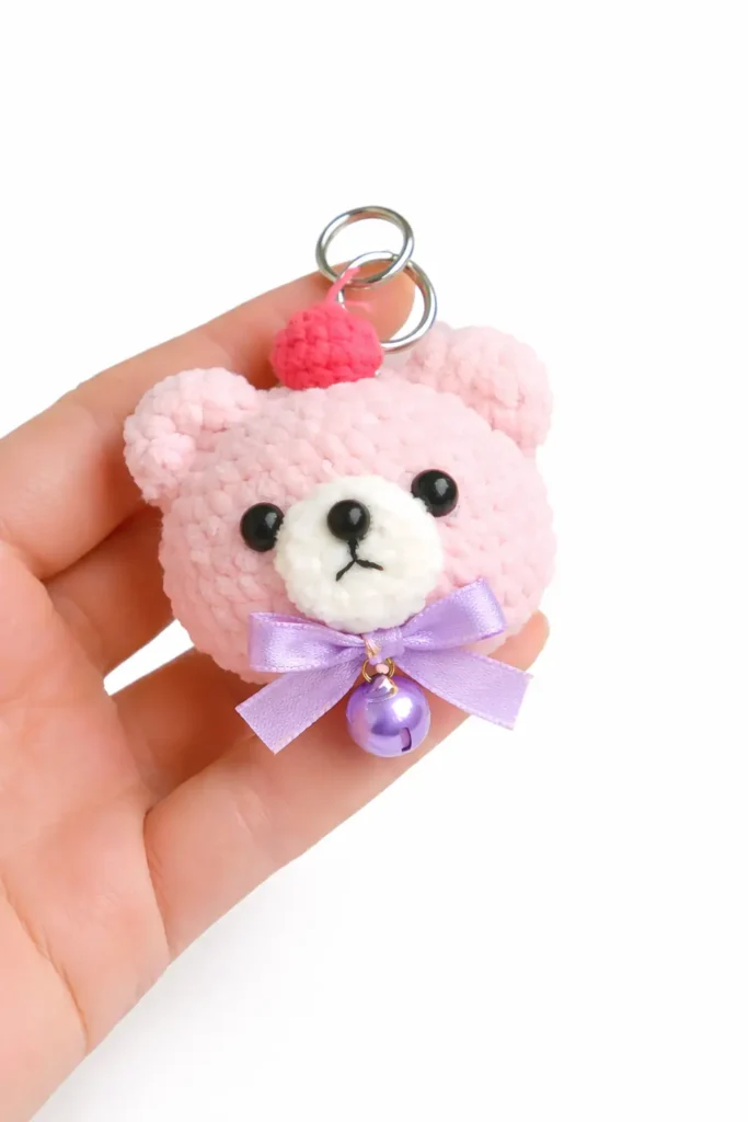 Mini bear crochet keychain pattern free close-up of a pink teddy bear keychain held in hand.