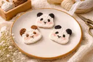 Flat Panda Applique Crochet Pattern: 7 Cute Ways to Use This Easy Design Flat panda appliquรฉ crochet pattern with three cute crochet animal face appliquรฉs displayed on a ceramic plate