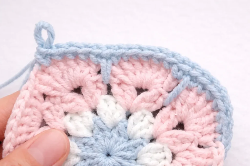 Pastel floral granny square crochet pattern close up of blue outline round