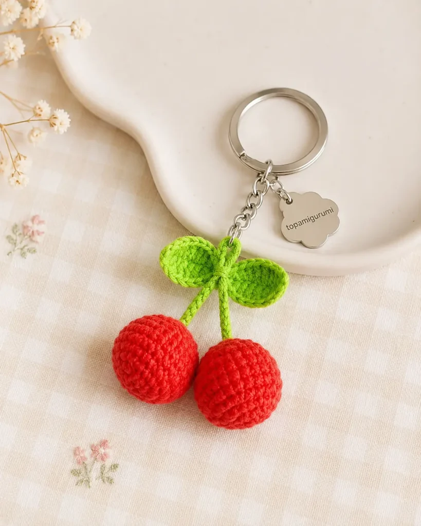 Cherry Keychain Crochet Pattern with two red cherries and green leaves